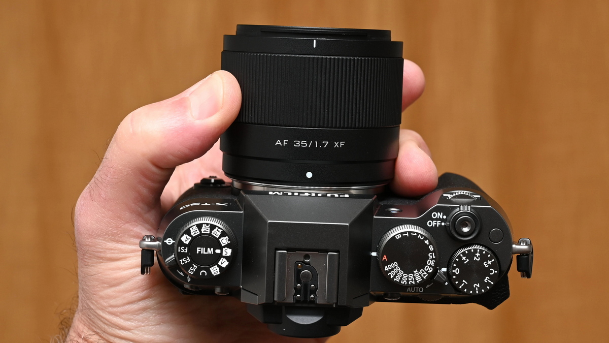 Об'єктив Viltrox AF 35mm f/1.7 Air на чорній тушці Fujifilm X-T50 у руці фотографа з видом на верхні диски управління